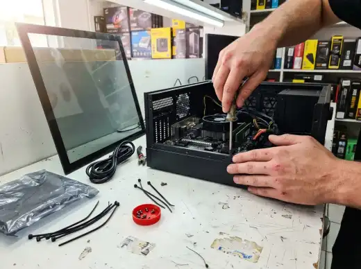 Mãos montando um PC numa bancada branca com chave de fenda, abraçadeiras e parafusos